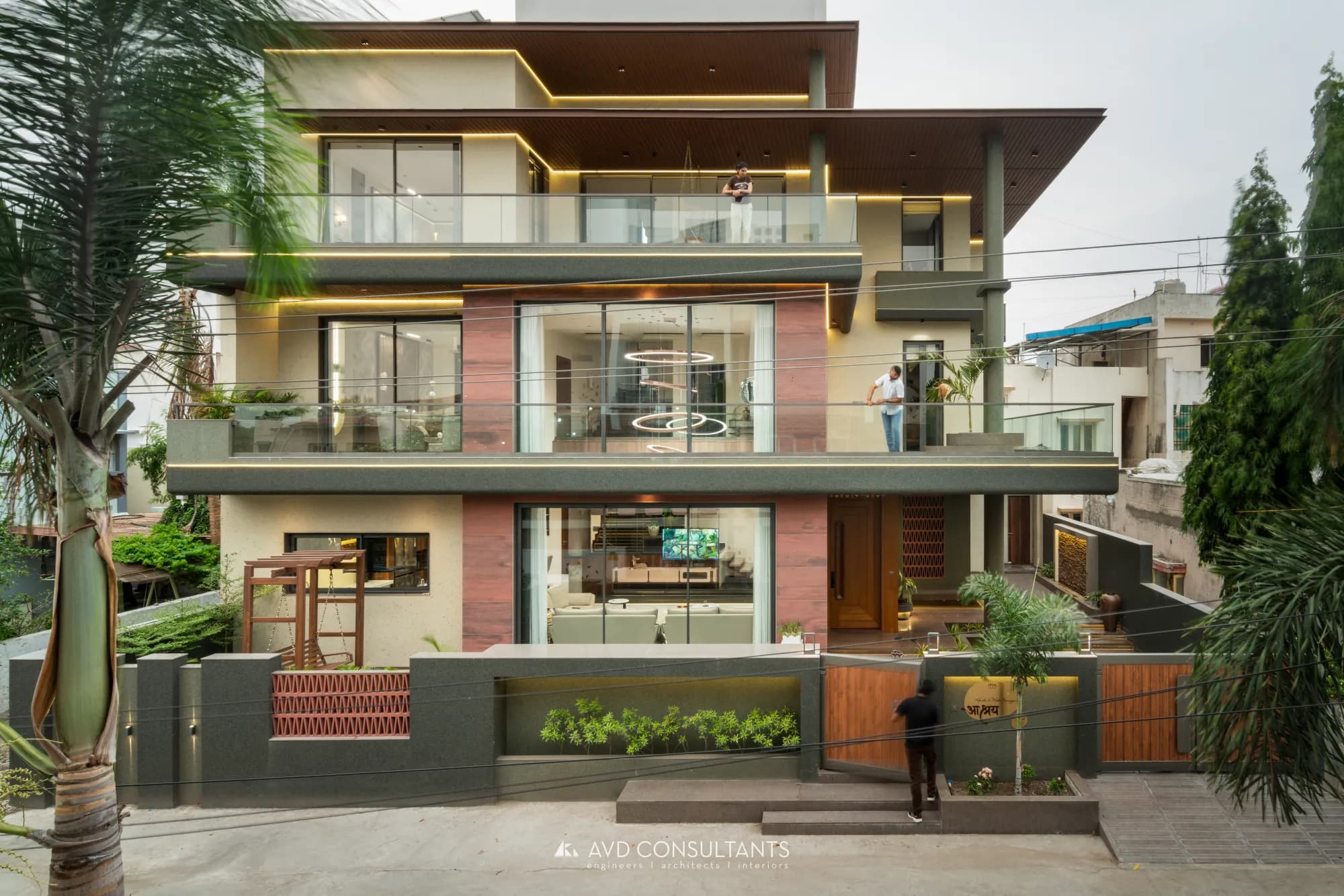 Aashray — Karangiya Residence — A bungalow arranged around a double-height living volume, a sculptural staircase and earthy stone finishes.