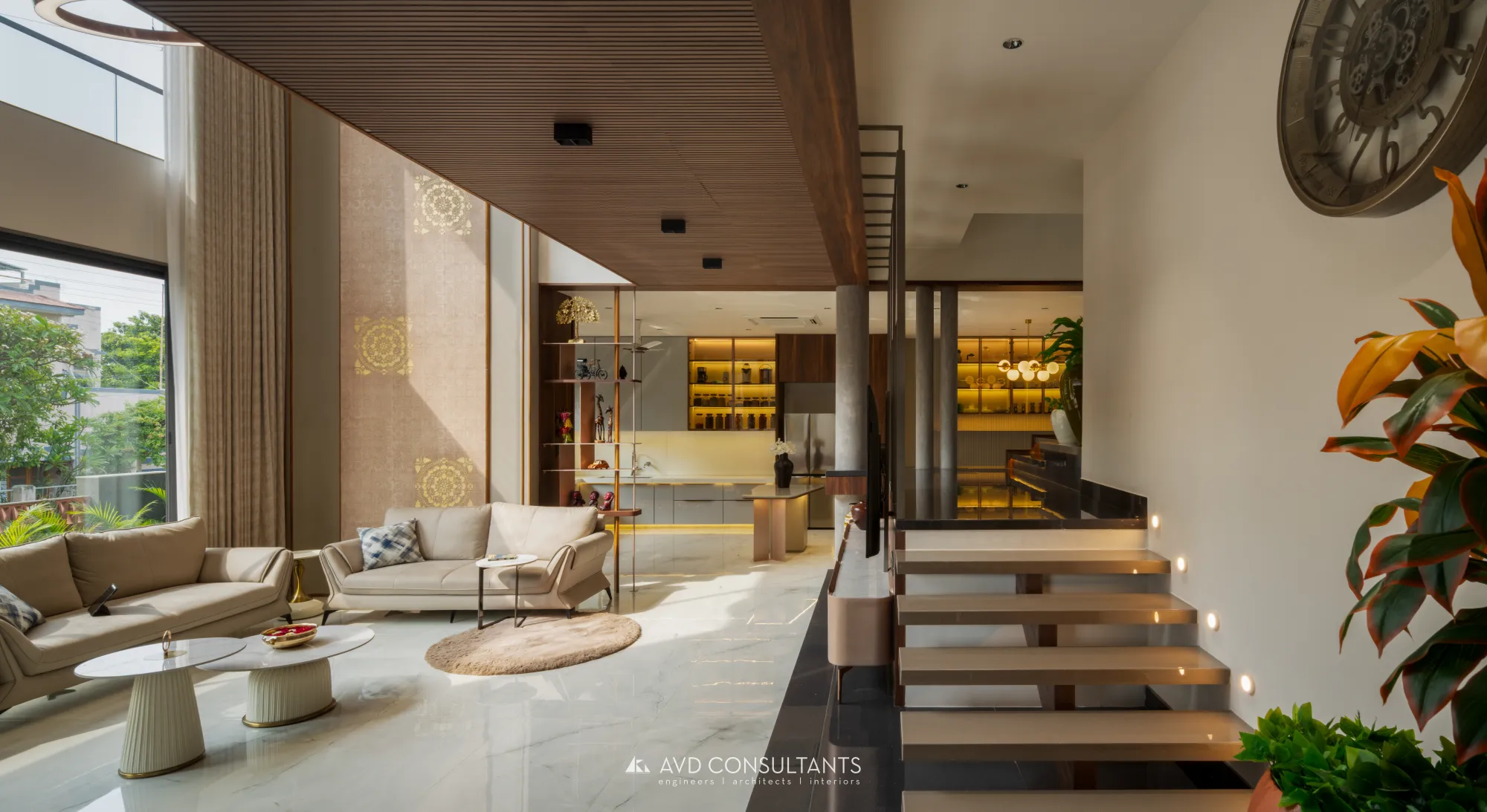 Aashray — Karangiya Residence — A bungalow arranged around a double-height living volume, a sculptural staircase and earthy stone finishes.